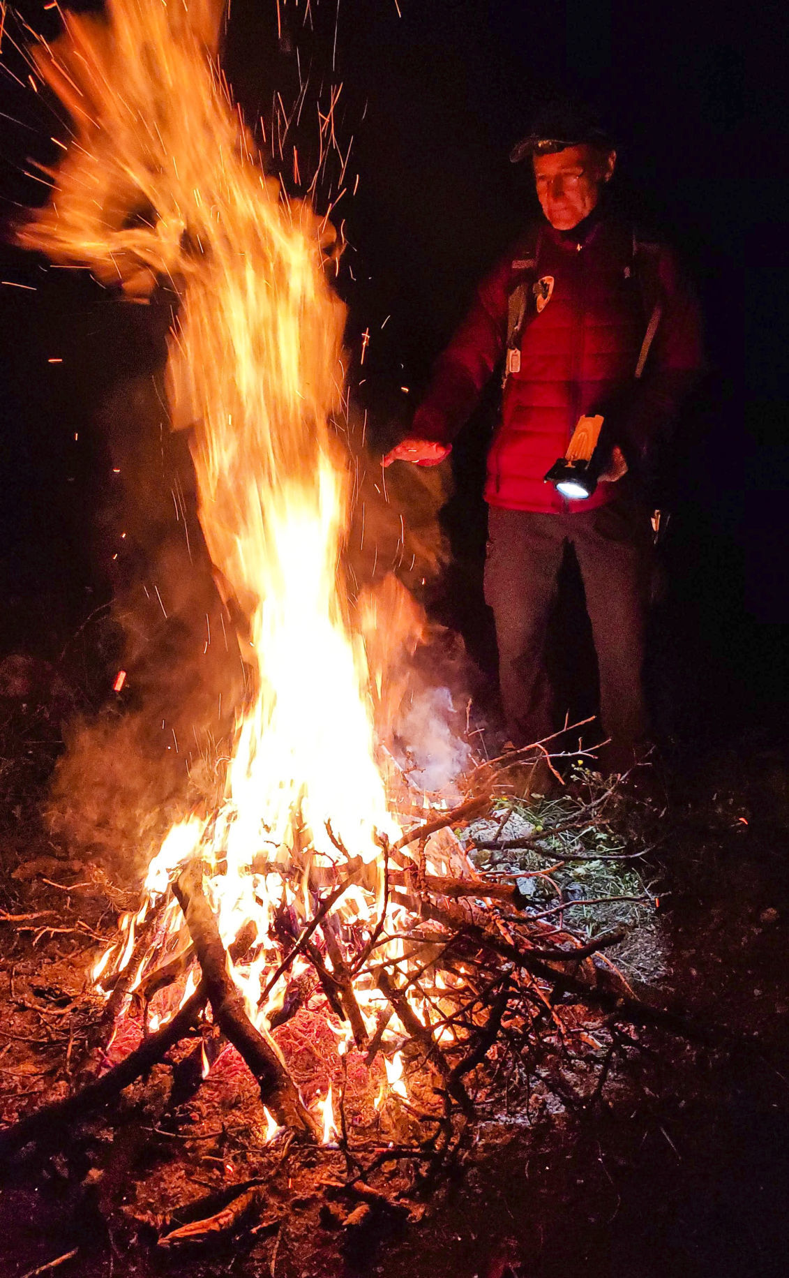 A search and rescue team member stands next to the fire